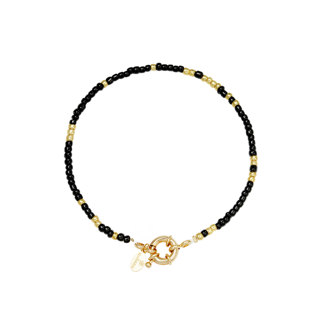 Armband Booka heeft kleine zwarte en goudkleurige beads en een slotje om bedels aan te hangen.
