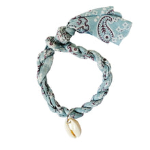 Load image into Gallery viewer, Armband van gevlochten stof met een schelpje als bedel. Armband is verkrijgbaar in verschillende kleuren: kobaltblauw, groen, roze, lichtblauw. 
