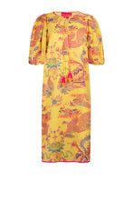 Load image into Gallery viewer, Gele Jurk van Place du Soleil, Oriental Dragon Yellow Midi is een prachtige middellange jurk met steekzakken, met half lange mouwen en onderjurk. De jurk heeft een V-hals met koord, flosjes en pofmouwtjes. De jurk is een recht model, heeft splitjes met biesjes aan de zijkanten en heeft een prachtige dragon print. 
