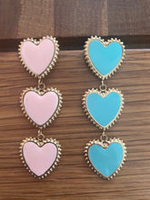 Load image into Gallery viewer, Oorbellen Hearts zijn mooie oorbellen, type oorstekers in kettingvorm van drie harten. Deze oorbellen zijn verkrijgbaar in verschillende kleuren: roze, blauw.
