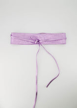 Afbeelding in Gallery-weergave laden, Lily is een leren wikkelriem in een metallic uitvoering. De riem is 8 cm breed en het taille gedeelte is 85 cm lang. Met de touwtjes kan de riem op een speelse manier om de taille geknoopt worden. De wikkelriem is verkrijgbaar in een maat.
